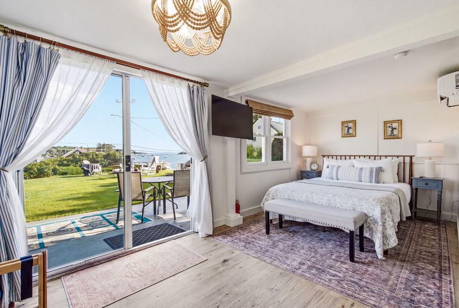 Bright Room 9 queen bedroom with TV and sliding doors opening to a private harbor-view patio.