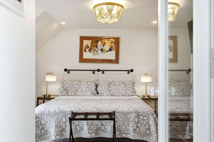 Bright king bedroom with patterned bedding, bedside lamps, and coastal-style decor.
