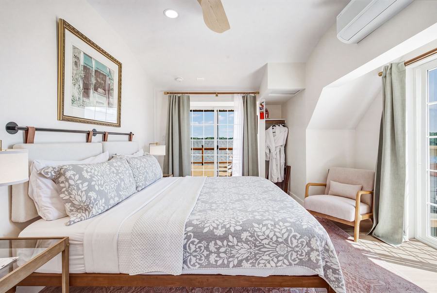 Bright king room with sitting chair, patterned bedding, and harbor-facing windows.