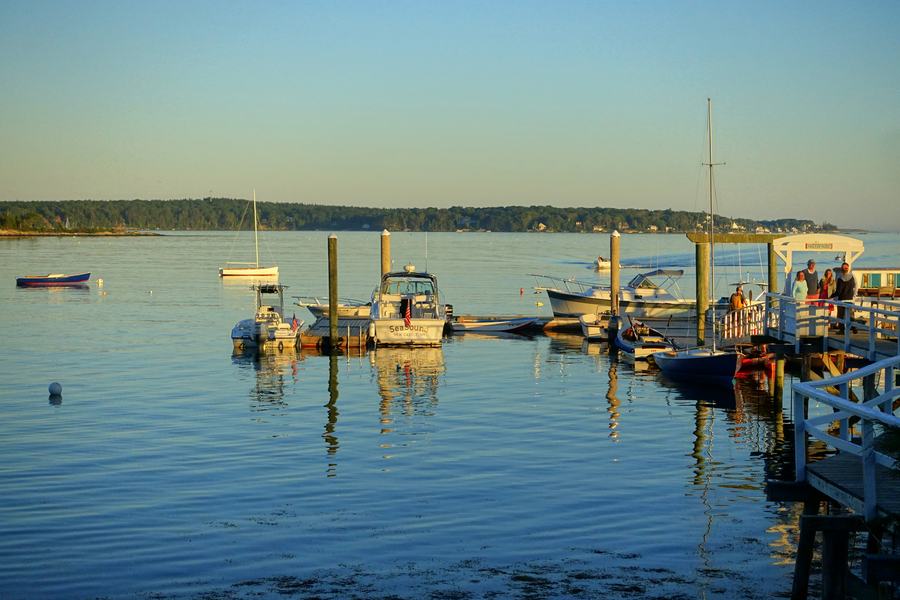 Visitors walking the waterfront at Boothbay Harbor, Maine, with fishing boats tied up at the docks