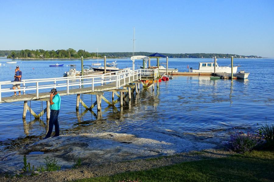 Boothbay Harbor waterfront in late summer with sailboats at their moorings and the town along the shore