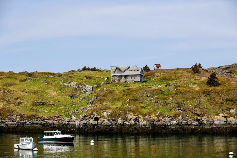 Rocky shoreline and fishing village on Monhegan Island seen from the water off the Maine coast